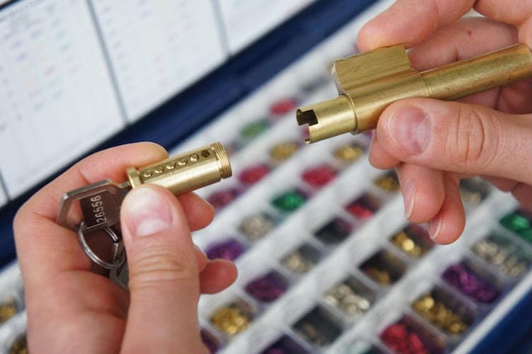 Rekeying a brass lock cylinder beside a locksmith pin kit of color-coded pins